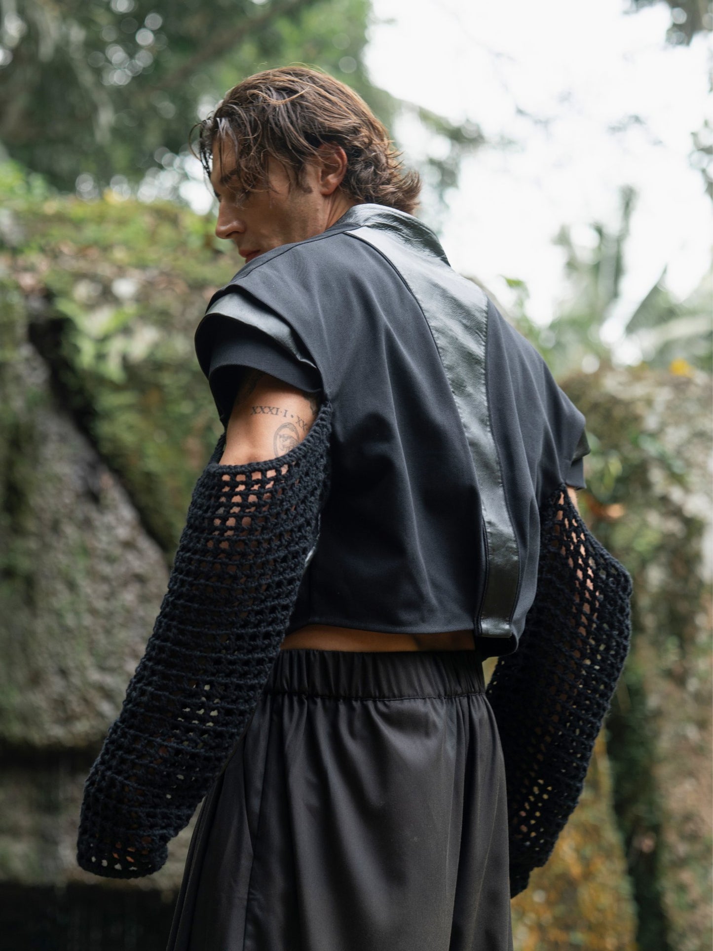 Black cropped denim jacket with knitted sleeves, leather inserts on the back and shoulders, and a bold, unique design that highlights individuality.