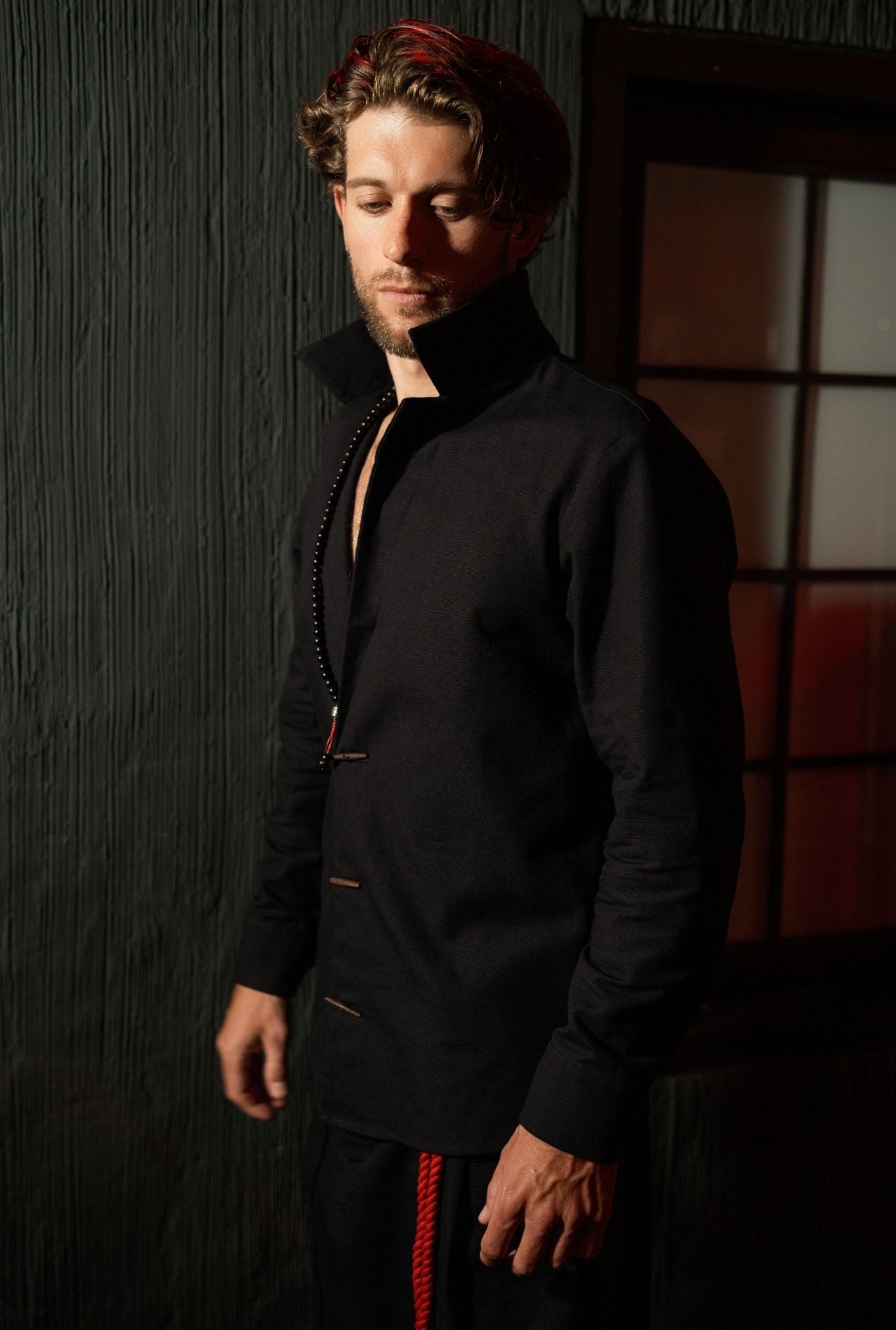 Designer black shirt-jacket menswear piece, lightweight structured fabric, relaxed silhouette, urban style look.