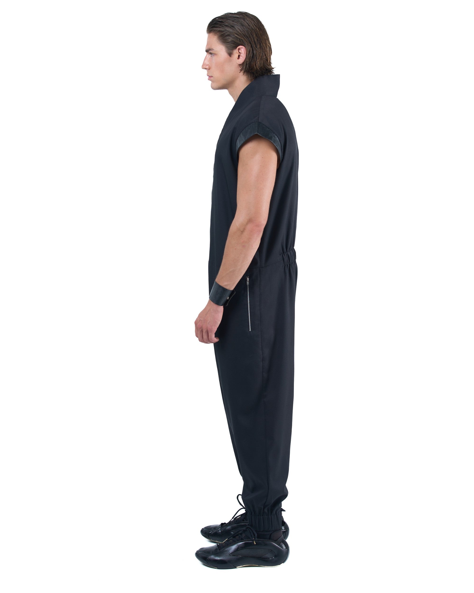 Black asymmetric jumpsuit with leather shoulders and diagonal zip closure by OVERZ
