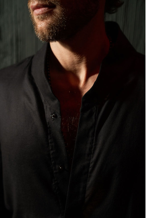 Close-up of black men’s designer shirt with clean collar and deep neckline, modern minimal menswear in Ubud