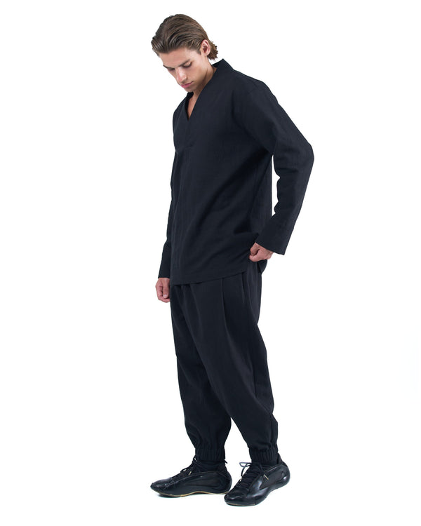 Black asymmetric jogger pants with elastic cuffs and textured fabric by OVERZ