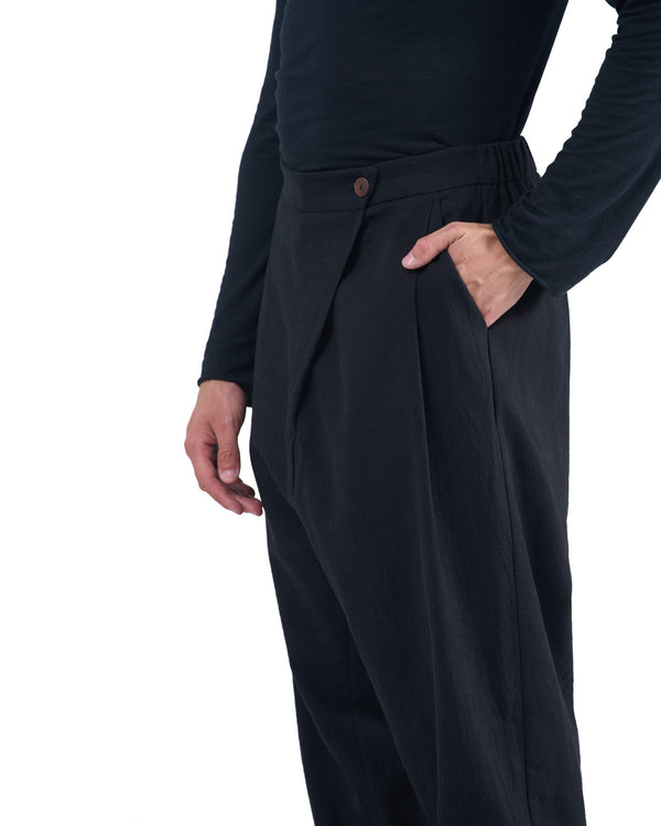 Black asymmetric jogger pants with elastic cuffs and textured fabric by OVERZ