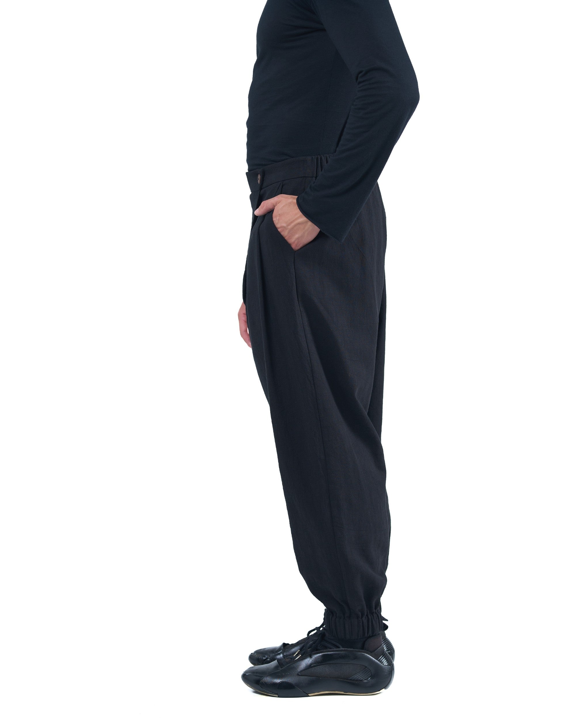 Black asymmetric jogger pants with elastic cuffs and textured fabric by OVERZ
