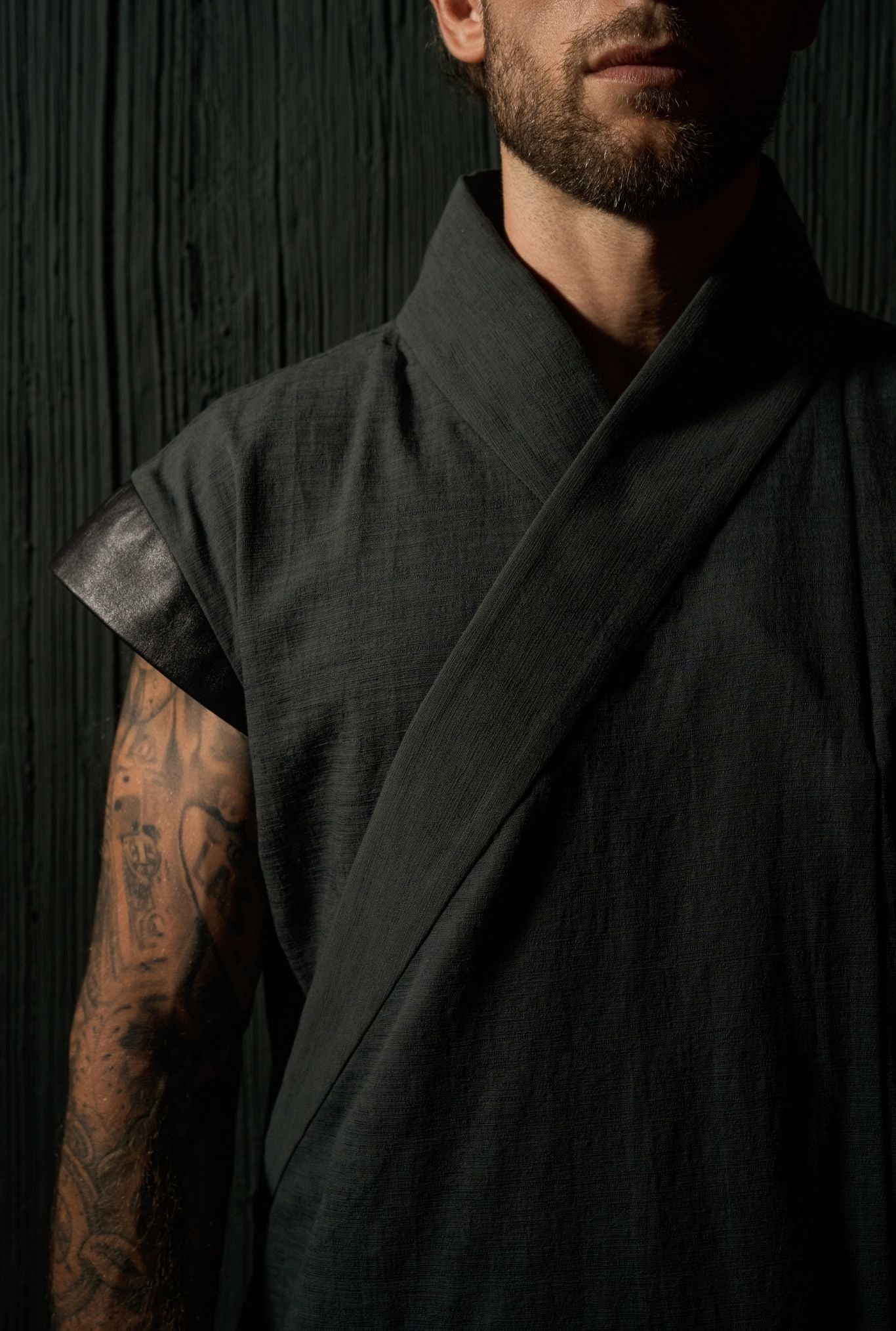 Black asymmetric wrap vest for men, side silhouette, architectural cut by OVERZ